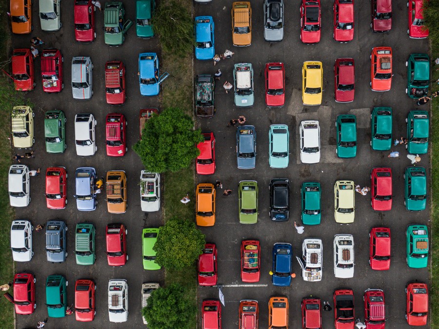 An aerial view of about 100 small cars of the same make and model parked in rows