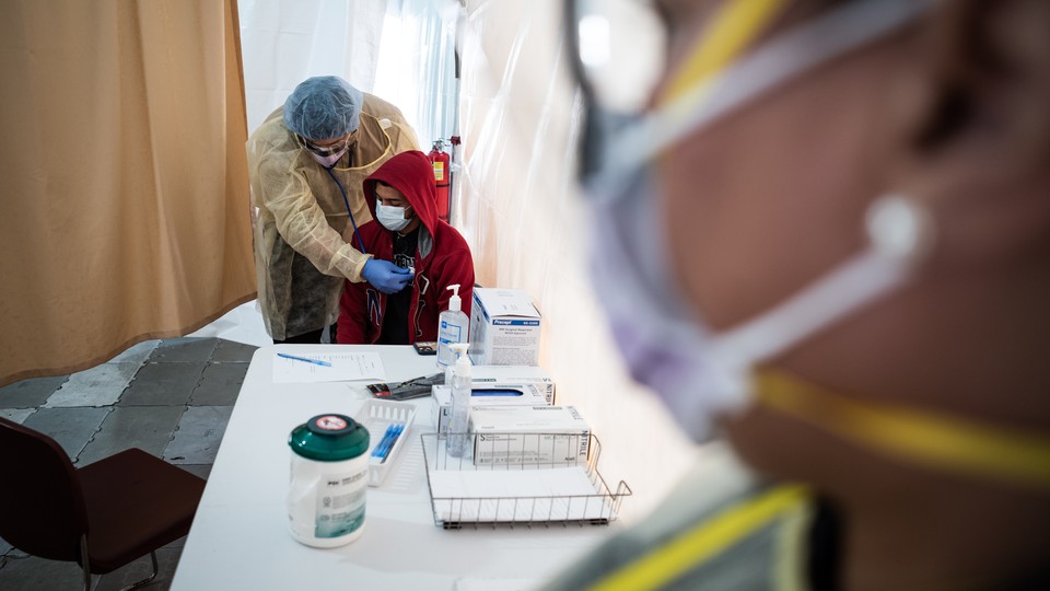 A doctor examines Juan Vasquez for a COVID-19 test inside a testing tent at St. Barnabas hospital on March 20, 2020 in New York City. St. Barnabas hospital in the Bronx set-up tents to triage possible COVID-19 patients outside before they enter the main Emergency department area.