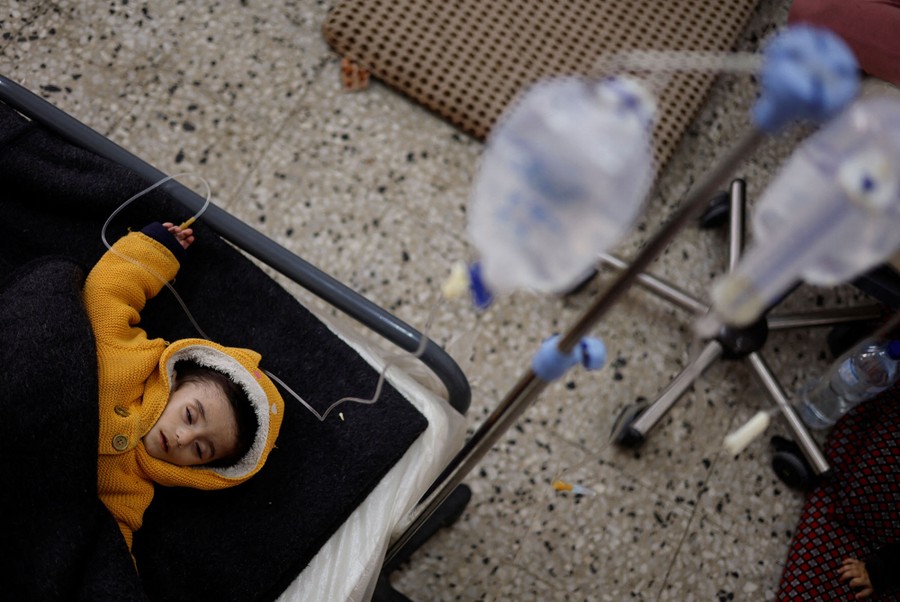 A young boy who is suffering from malnutrition lies on a bed, receiving treatment at a health-care center.
