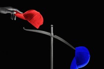 A hand placing a red hat on a scale