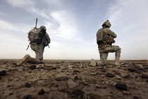 Two soldiers kneel on the ground in Afghanistan.