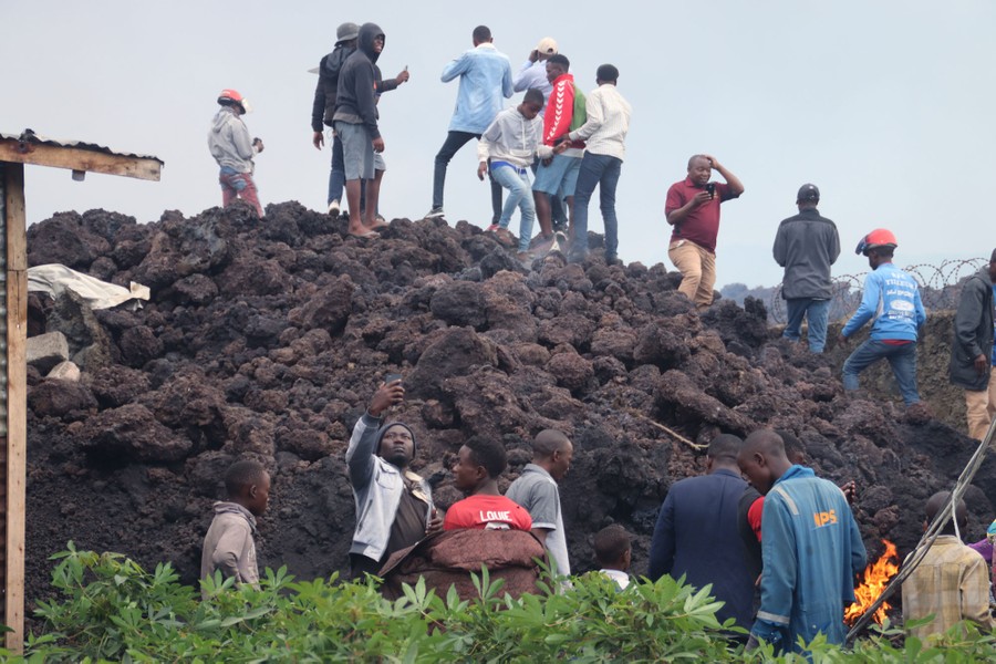 People climb on a large pile of volcanic rock.