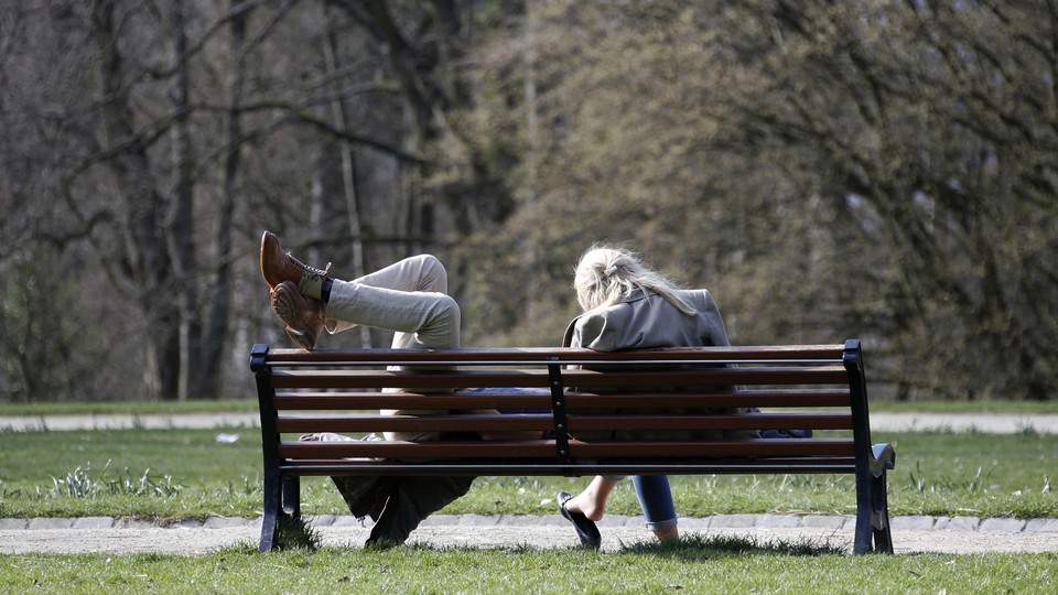 One person sitting and the other lounging with feet up on a bench