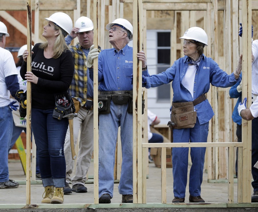 Several people work together to erect a wall on a construction project.