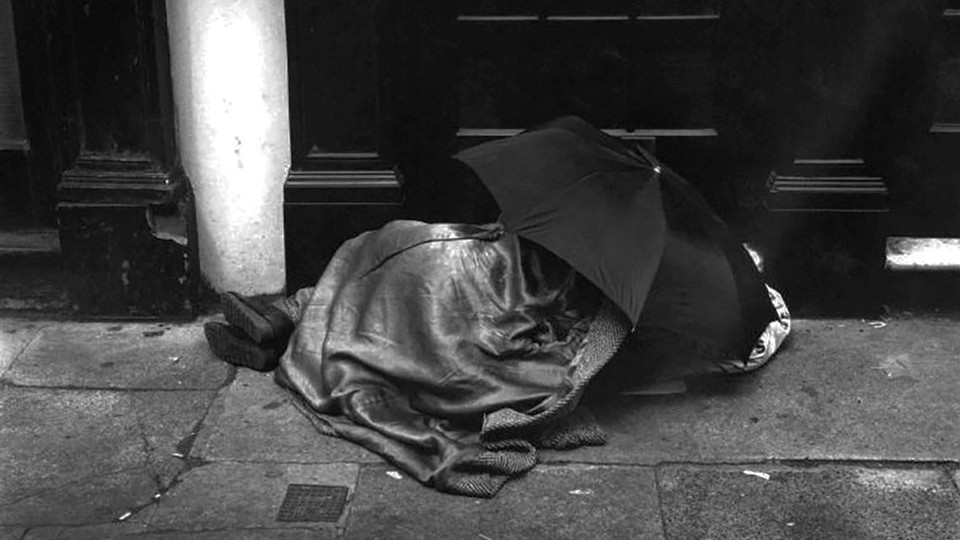 An unsheltered person sleeping under an umbrella in London