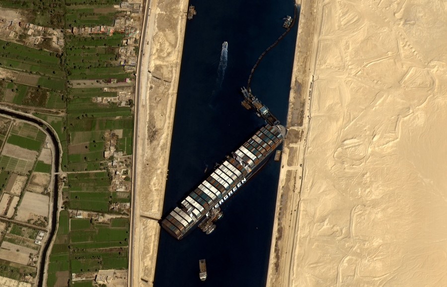 A satellite view of a container ship stuck at an angle in a canal.