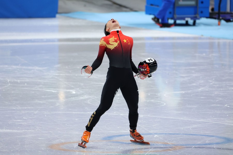 A skater standing on the ice, seen with his head back and mouth open, celebrating a win.