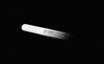 A pregnancy test coming out of the shadow of a black background