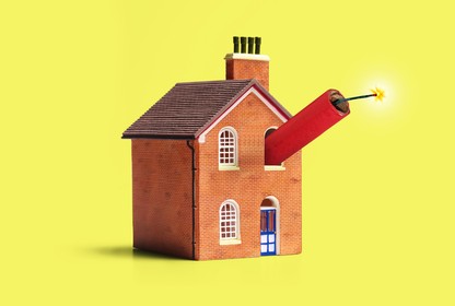 A house with a lit stick of dynamite sticking out of a window