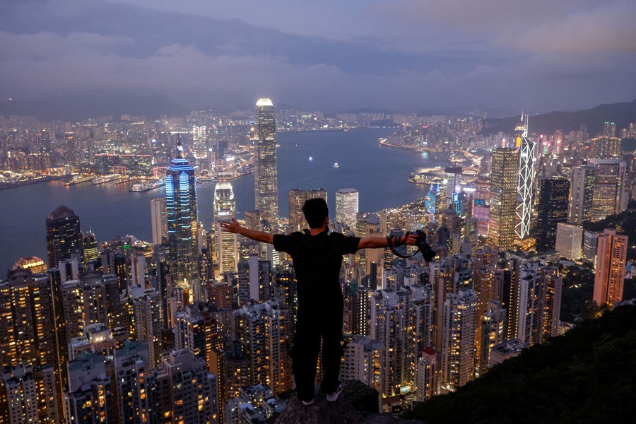 A person poses for a photo at a lookout above the buildings of Hong Kong.
