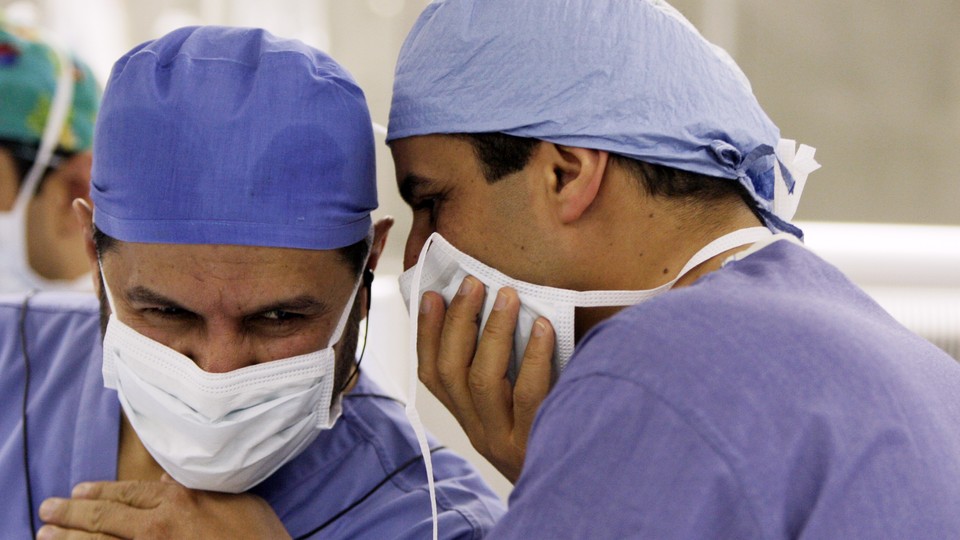 Former Saudi Health Minister Abdullah al-Rabia and a doctor, pictured in scrubs and surgical masks, consult during a surgery in 2010.