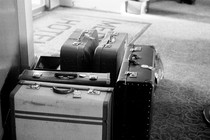 A black and white photograph of suitcases sitting by an entryway