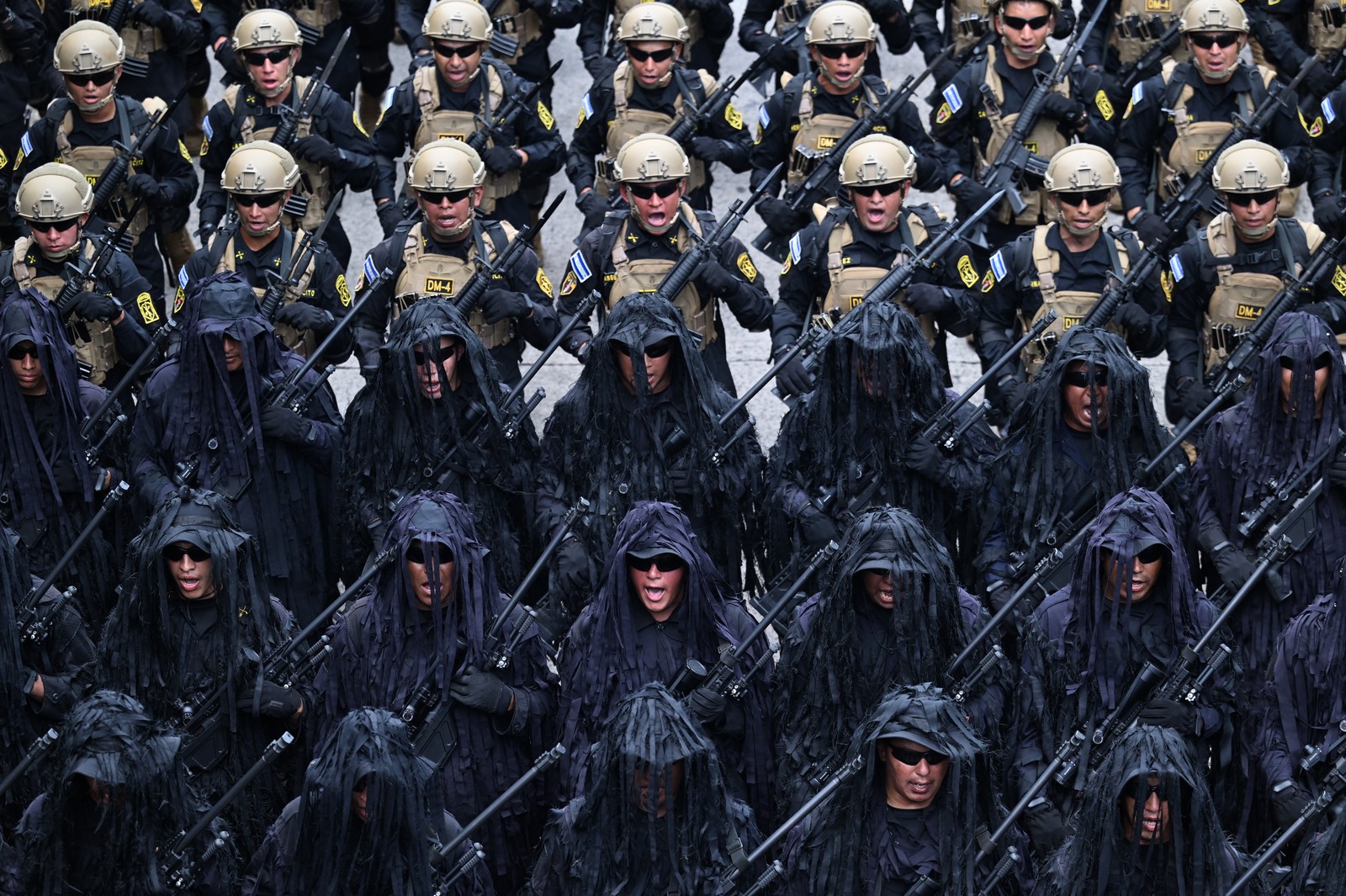 Soldiers in varying uniforms march during a military parade.