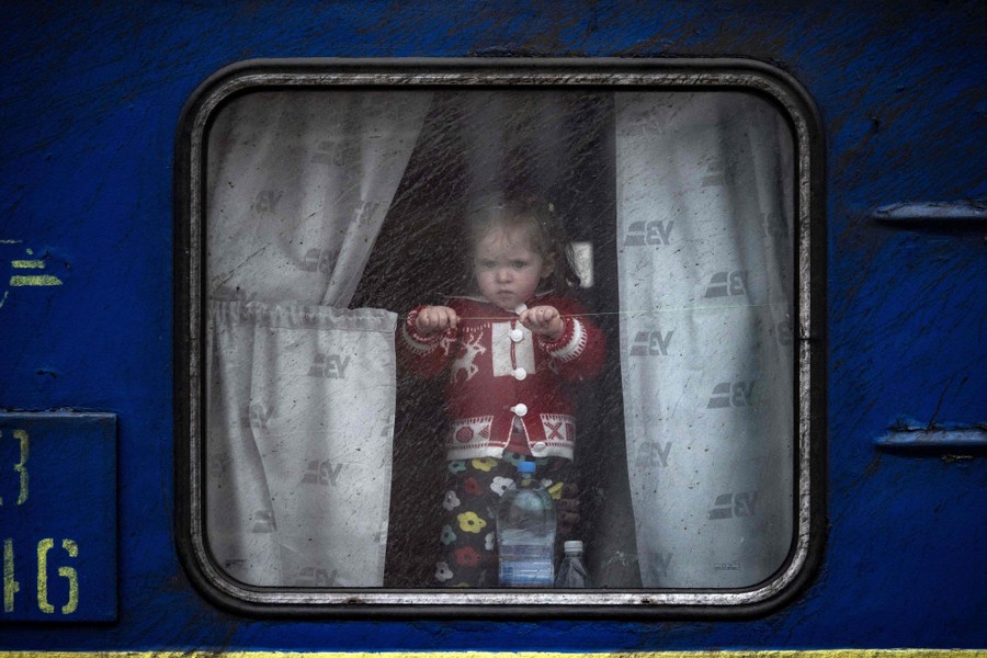 A small child looks out the window of a train.