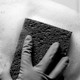 A gloved hand using a sponge to clean a tiled wall