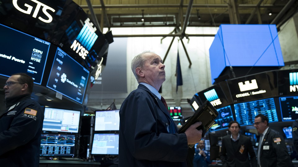 A trader looking up at screens on the stock exchange floor