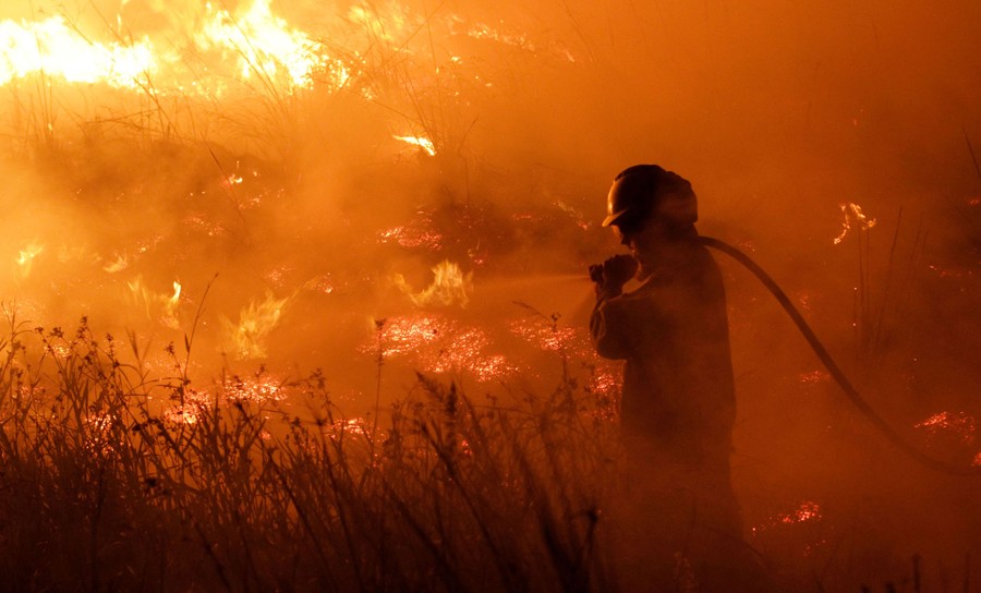 A firefighter uses a hose to battle a wildfire.