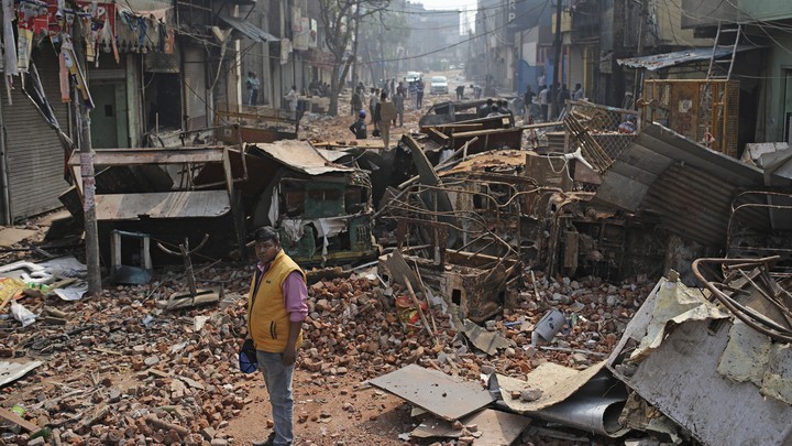 A Delhi municipal worker on a street vandalized in Tuesday's violence in New Delhi, India.