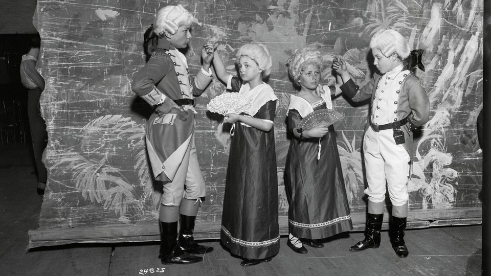 Children in colonial-era costumes on a theater stage.