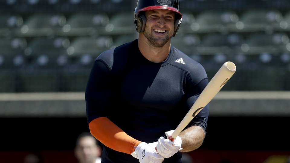 Former NFL quarterback Tim Tebow smiles during a workout for baseball scouts and the media during a showcase at the University of Southern California on August 30, 2016.