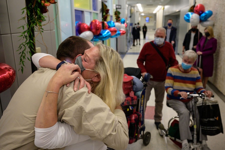 People embrace in an airport hallway.