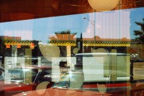 A view into a dimly lit room with a bright sky and a car reflecting onto the window