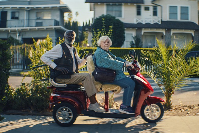 Older man and woman on a red electric scooter