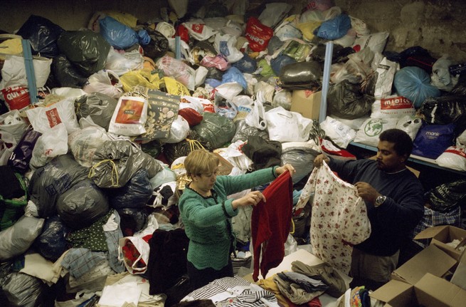 People sorting through enormous piles of recycled clothing.