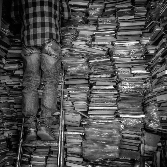 man in front of a pile of books
