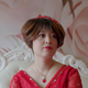 Closeup of Gai Qi, one of the women in the documentary, wearing a red dress against a pink backdrop.