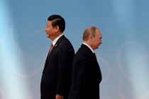 Xi Jinping and Vladimir Putin stand back to back in black suits, Xi towering over Putin.