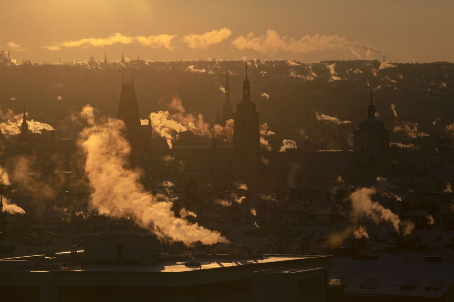 Smoke and steam rises from chimneys above a city.