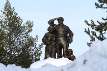 A bronze statue of travelers surrounded by snow