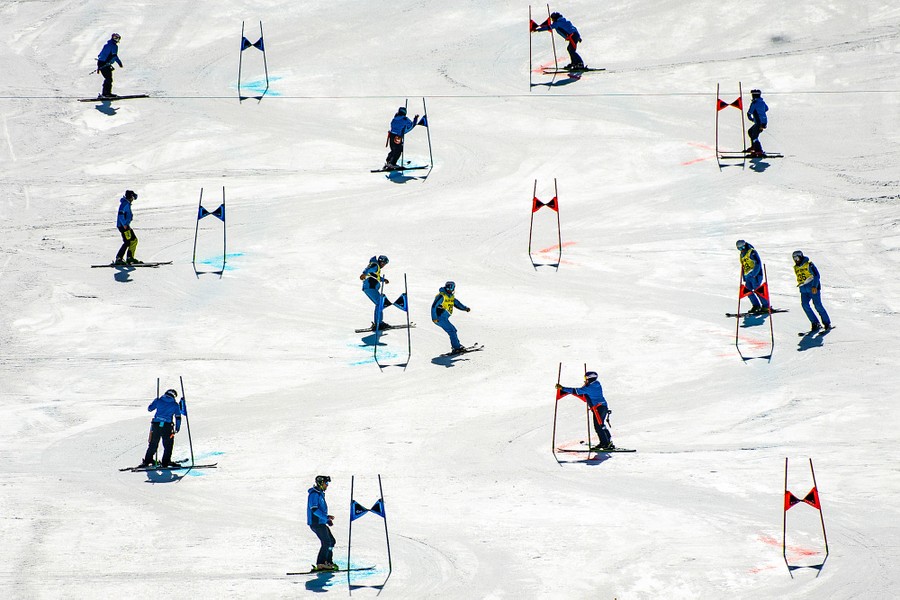 A dozen workers tend to a course on a ski slope.