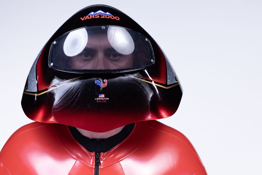 A skier wears a broadly rounded helmet and smooth ski suit for a portrait.