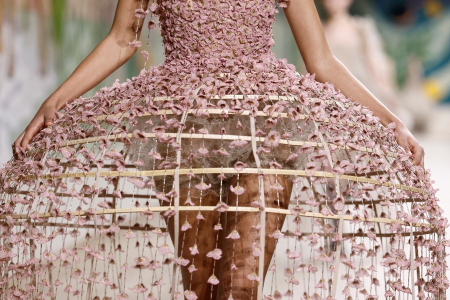 A model wears a hoop skirt covered in small bits of cloth.