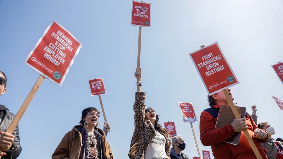 Labor-union organizers holding signs that read, "Rebuild a Fighting Labor Movement!," "Demand Starbucks Stop Cutting Employee Hours!" and "Fight Starbucks' Union Busting!"