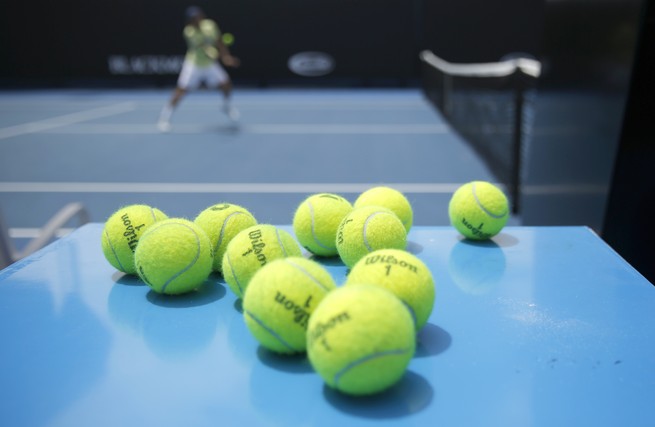 Eleven tennis balls near a tennis court 