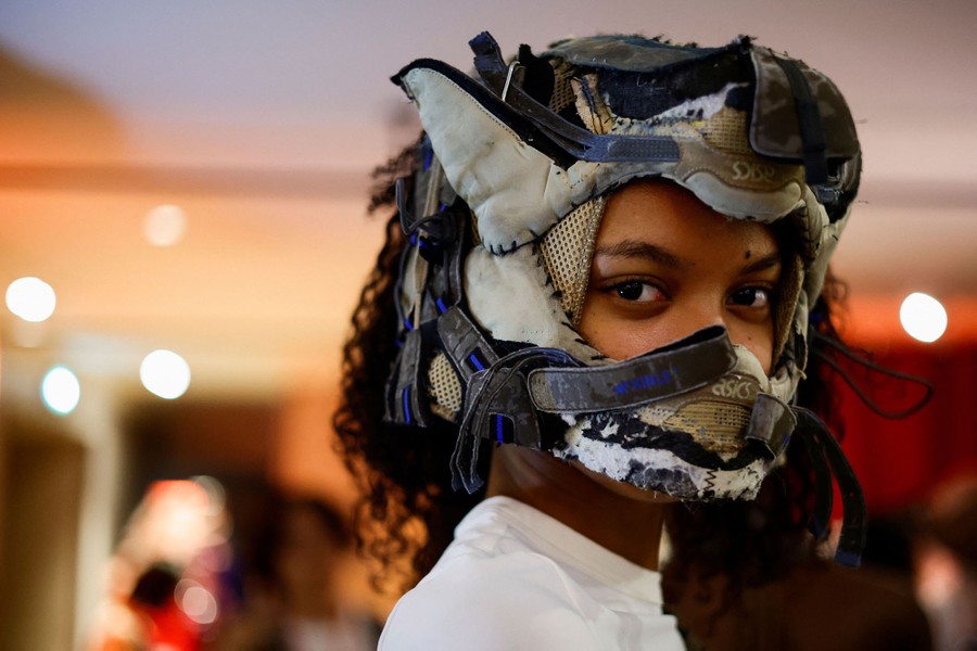 A model poses while wearing head gear made out of what appears to be sneaker parts.