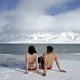 People in bathing suits sit atop an ice mass