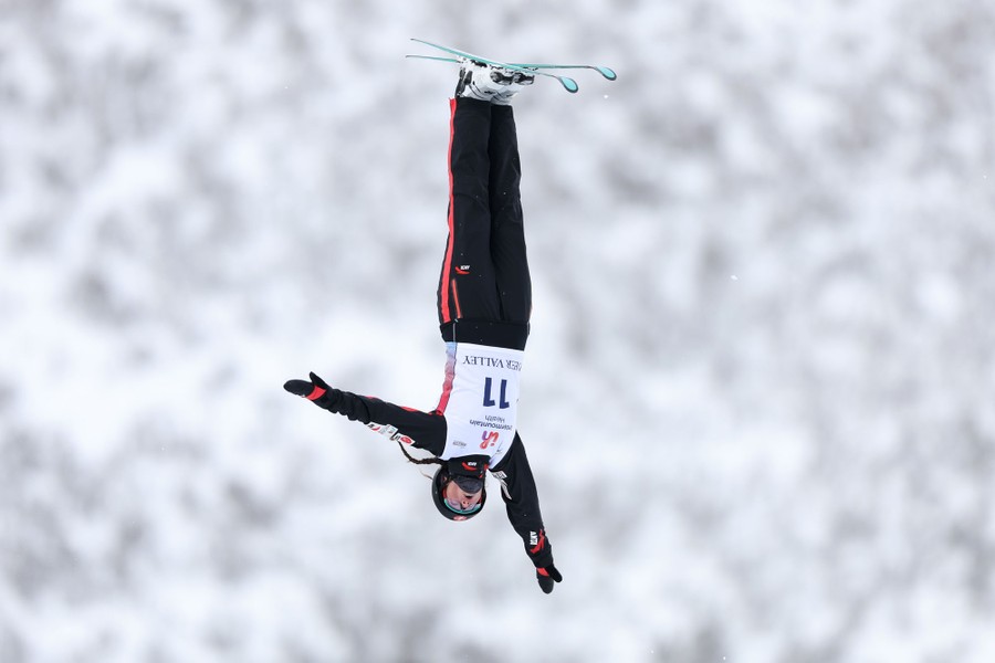 A skier is photographed in midair, upside down, during a qualification run.