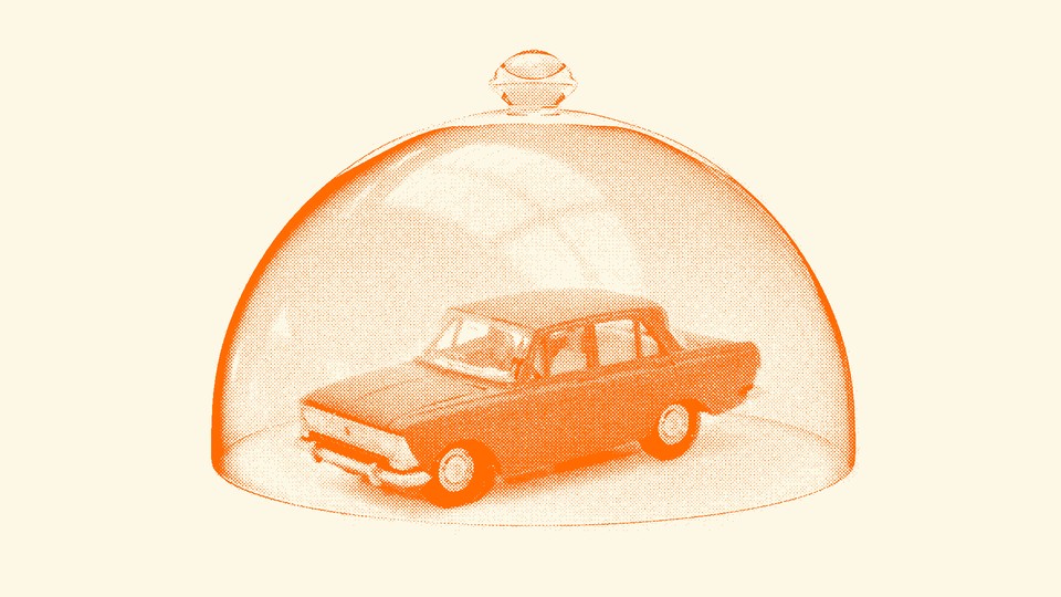 A vintage car sits inside of a glass dome