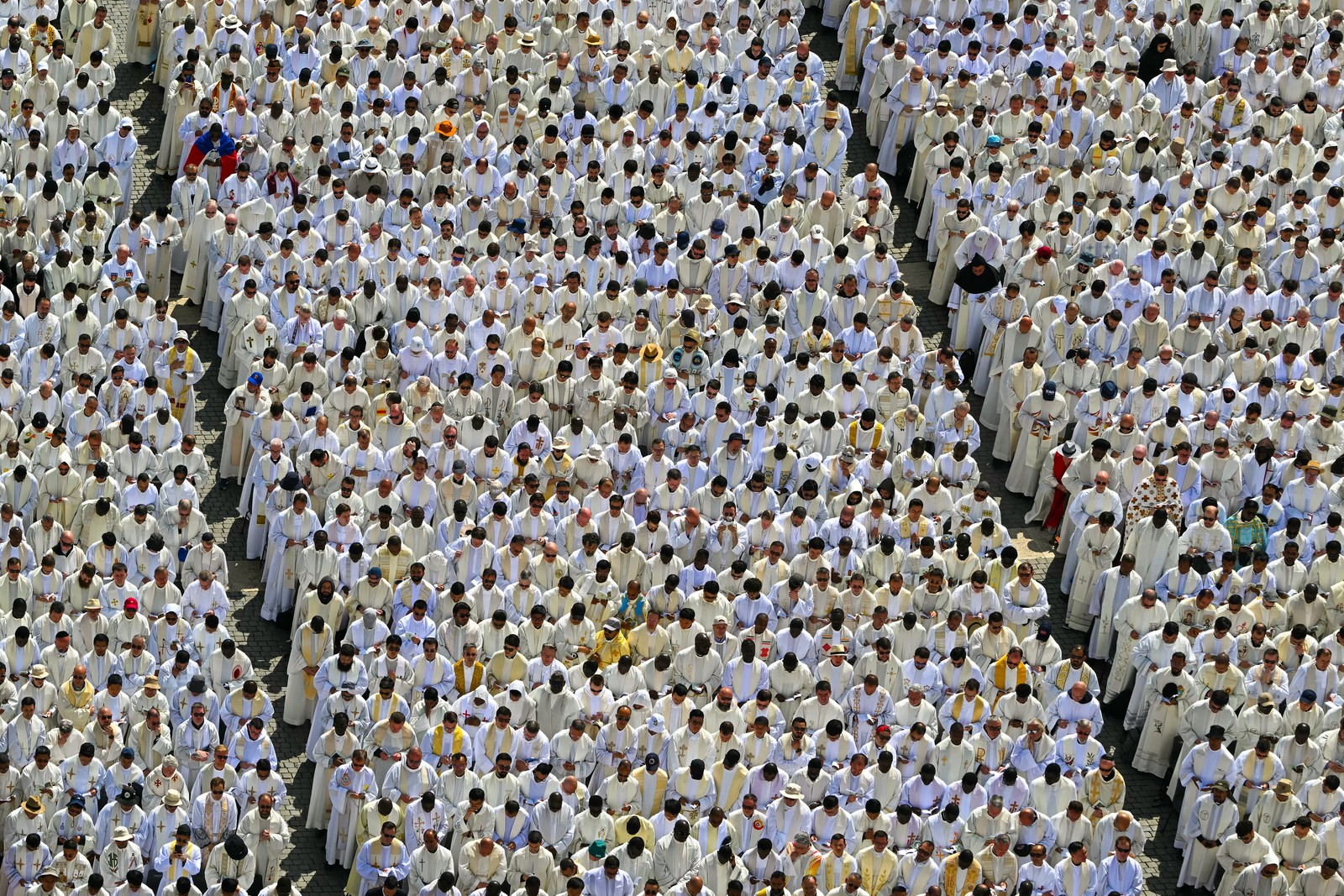 Many rows of priests stand during a ceremony at the Vatican.