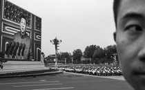 A black-and-white photo of Xi Jinping appearing on a huge screen at a rally in China.