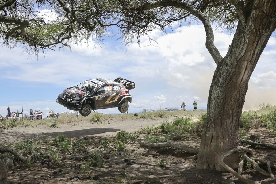 A rally racing car passes by, seen in mid-air after a jump.