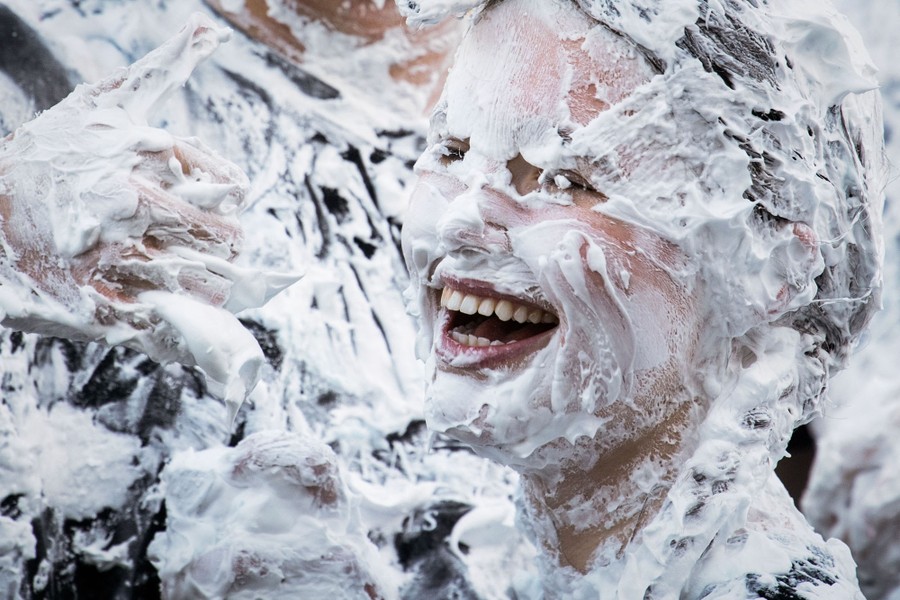 College students, covered in shaving foam, laugh and play.