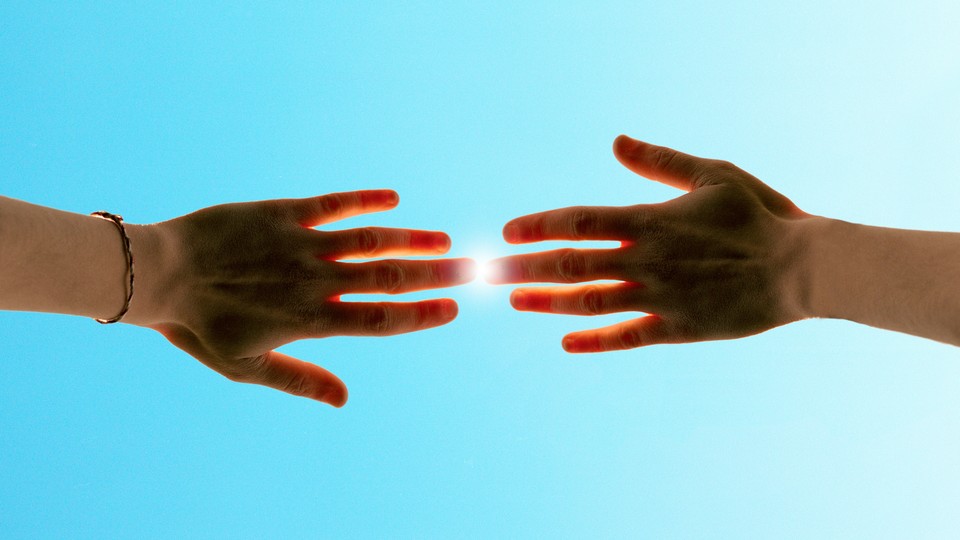 Two hands, raised to the sky, touching as the sun beams down between them