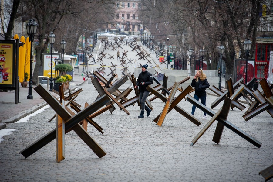 People walk among anti-tank barriers in a city street in Ukraine.