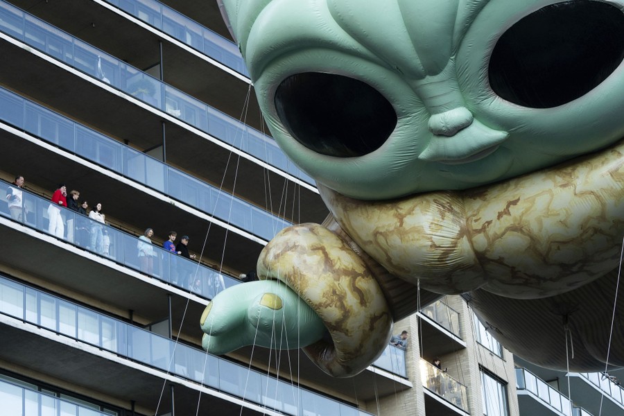 People watch from their balconies as a huge tethered balloon of a character from Star Wars floats past.