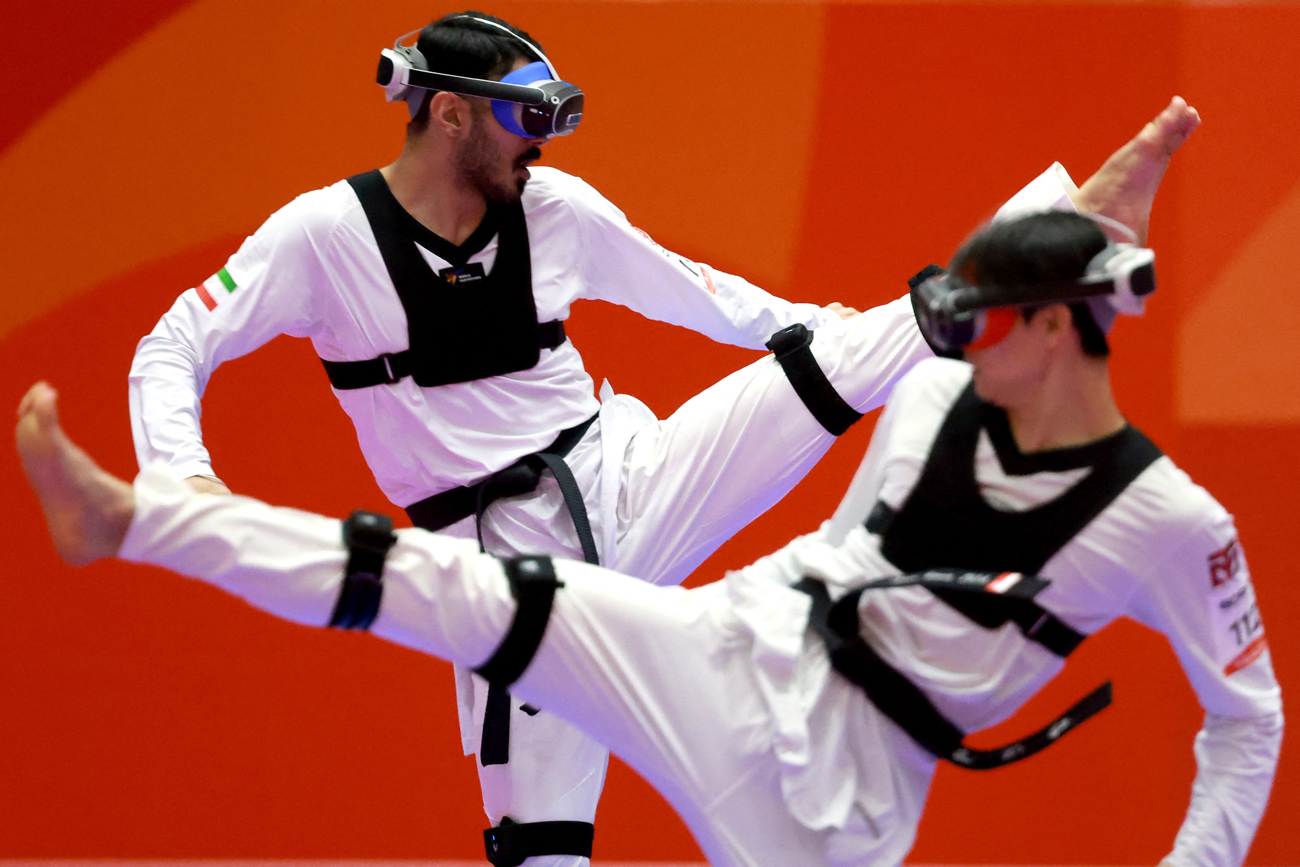 Two athletes wearing virtual reality goggles kick as they compete in a 'virtual taekwondo' event.